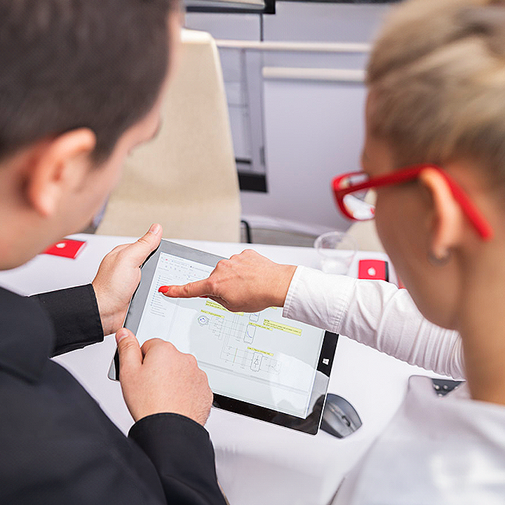 A man and a woman focused on a tablet, engrossed in its contents.