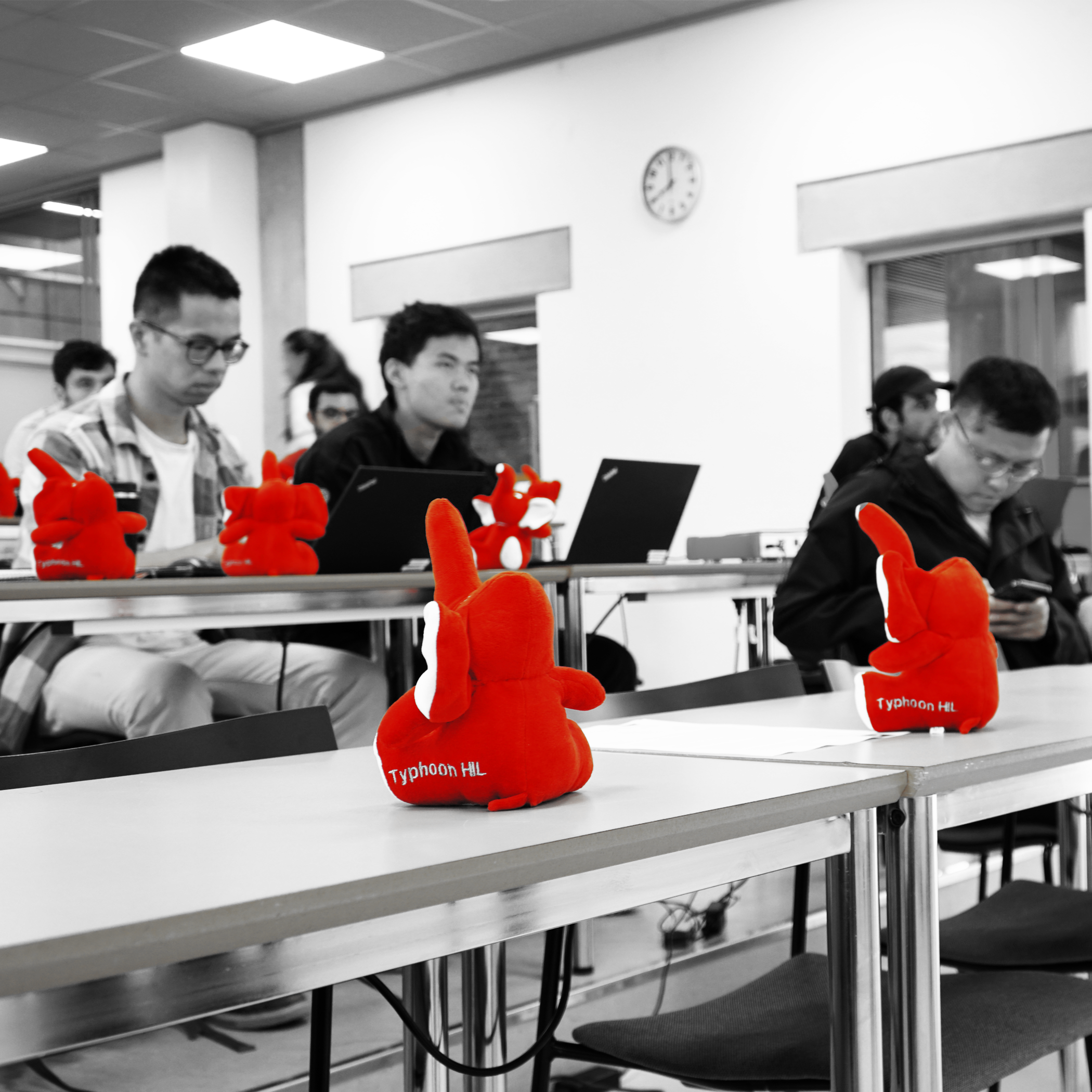 A group of people sitting in a classroom, with stuffed red elephants on their desks.