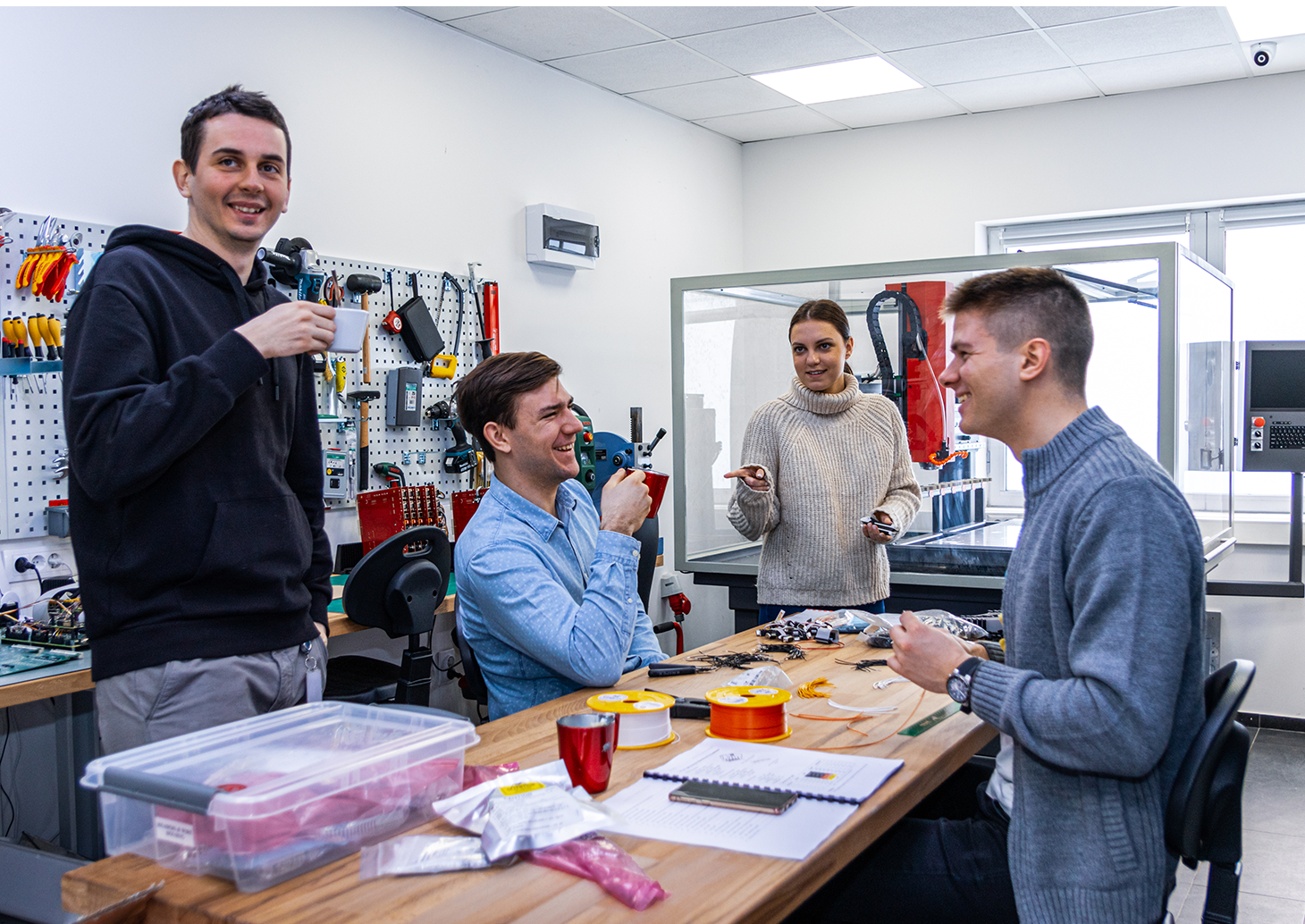 Four individuals from hardware team, smiling and collaborating on a project.