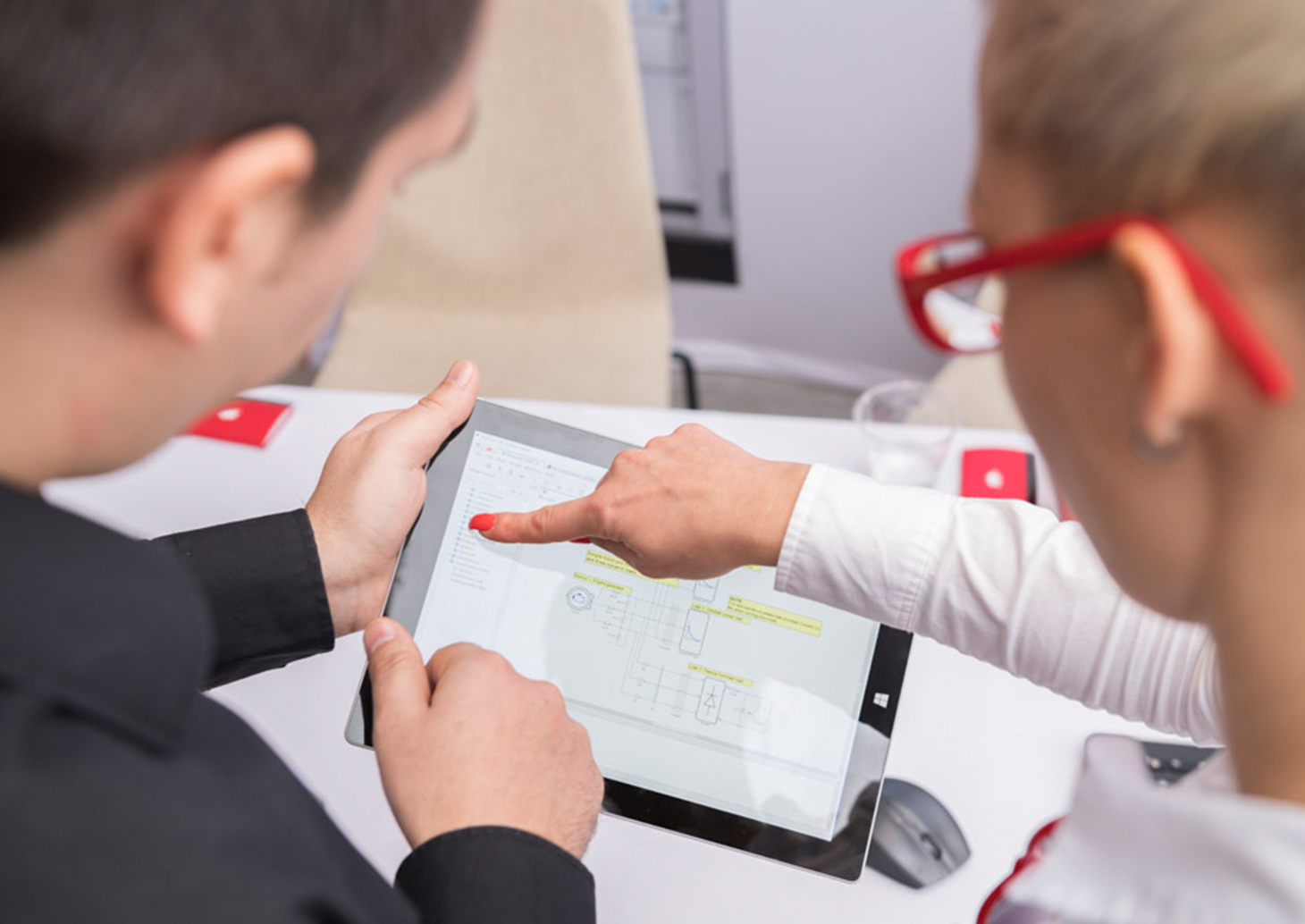 Two people focused on a tablet screen, engrossed in its contents.