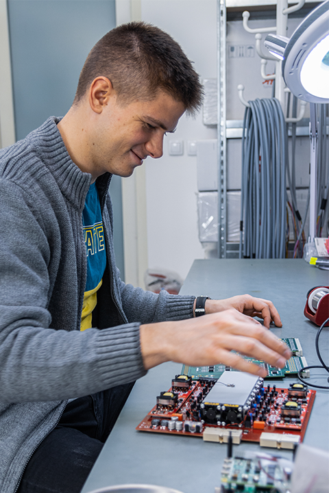 A man working on a PCB board and smiling.