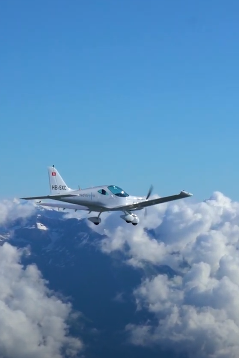 A small H55 airplane flying through the clouds.