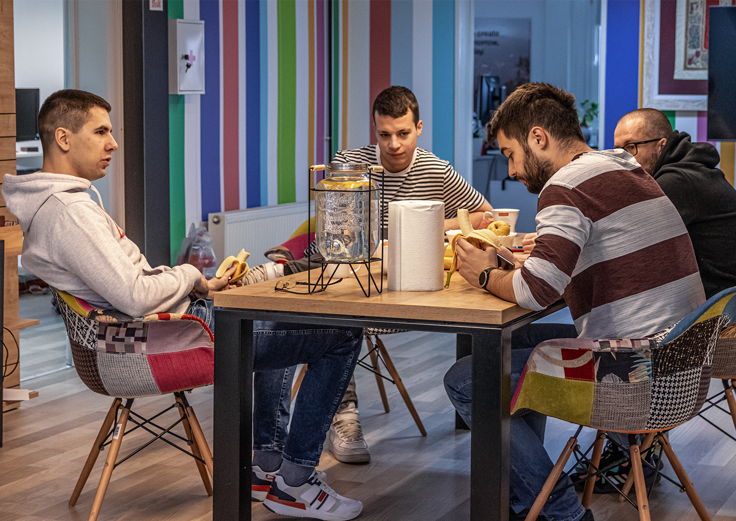 Four men enjoying a meal together at a table, savoring their food and engaging in conversation.