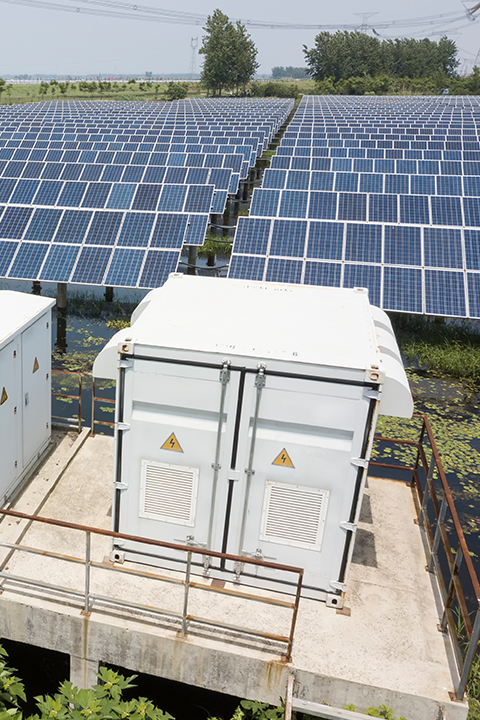 Solar converter cabinet with solar panels in the background.