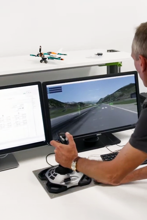 A man engrossed in an airplane drive simulation, focused on two computer monitors displaying the simulated environment.