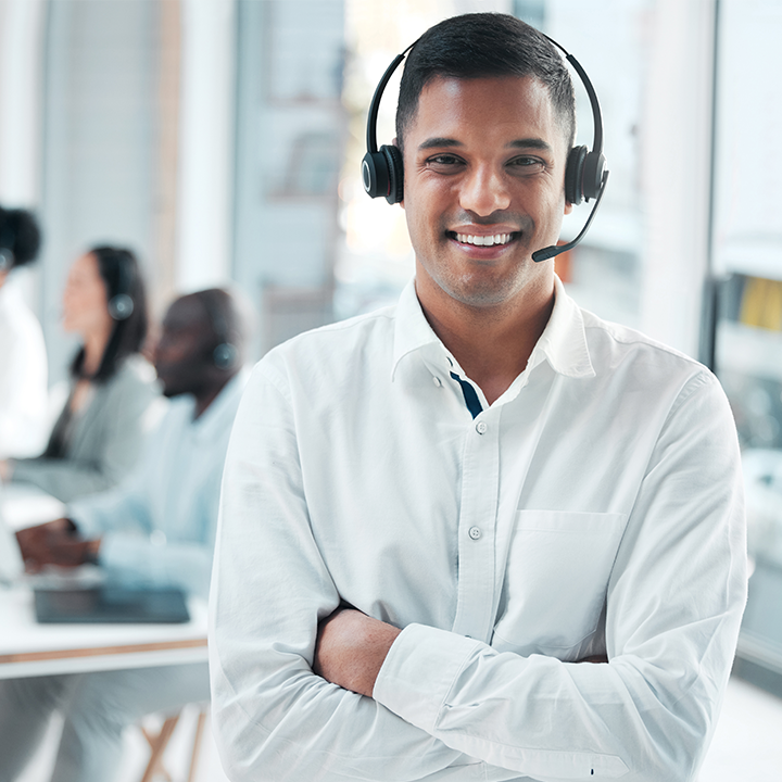A smiling man in an office, wearing a headset, indicating his availability for support.