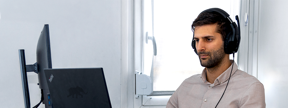 A man wearing headphones, focused on his computer screen.